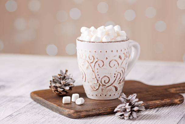 Mug with coffee and marshmallow, knitted scarf and garland on wooden table. Autumn mood. Hygge concept - Фото, изображение