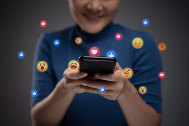 Femme asiatique utilisant le téléphone intelligent pour les médias sociaux avec bulle émoticône. Isolé sur fond. - Photo, image