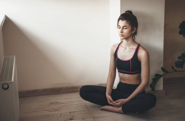 Home Yoga-Sitzung einer kaukasischen Frau in Sportbekleidung, die auf dem Boden in der Nähe des freien Raums meditiert - Foto, Bild