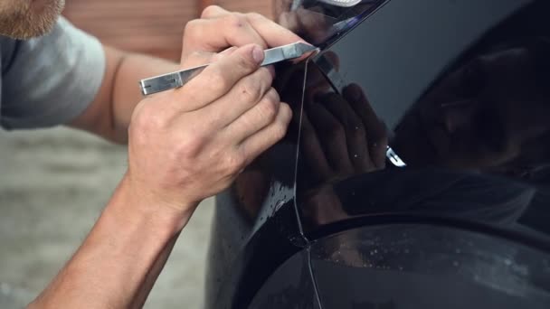 Detailfilm verf bescherming mannen specialist snijden en inpakken auto in de garage showroom, beschermende coating installatie - Video