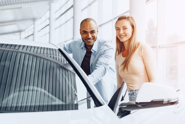 Young happy couple choosing a car in car dealership - Fotoğraf, Görsel