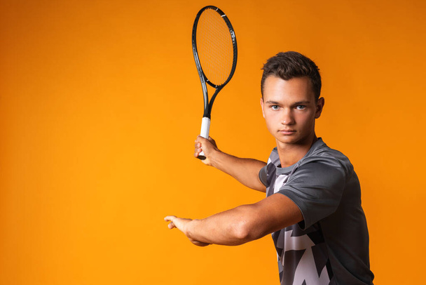 Portrait of a young man tennis player on orange background - Фото, зображення