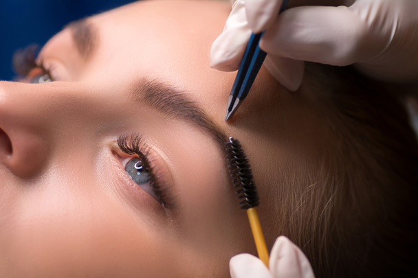 Beautician plucking eyebrows. Eyebrow care in a beauty salon - Фото, изображение