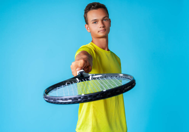 Young man tennis player in sportswear posing against blue background - Fotó, kép