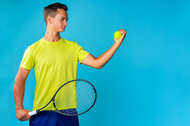Young man tennis player in sportswear posing against blue background - Foto, Bild