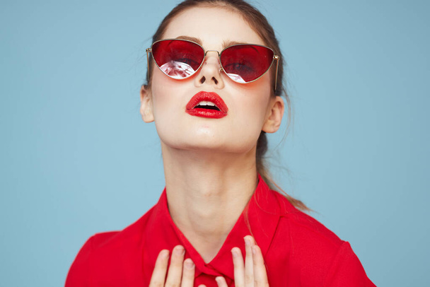 Mujer encantadora en gafas oscuras maquillaje brillante labios rojos glamour fondo azul - Foto, Imagen