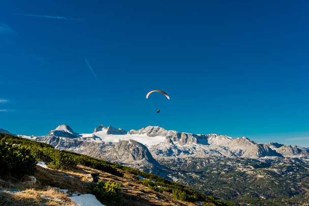 Αλεξίπτωτο που πετά στον γαλάζιο ουρανό πάνω από τα βουνά των Άλπεων - Φωτογραφία, εικόνα