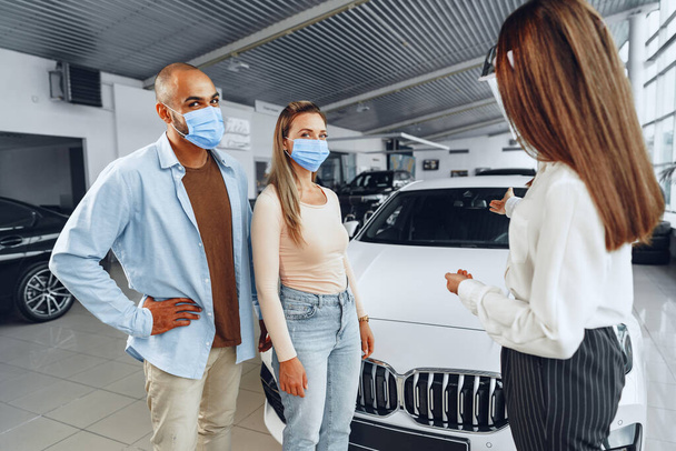 Woman car dealer consulting buyers wearing medical face shield - 写真・画像