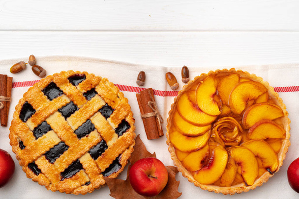 Autumn thankgiving pies on white wooden board decorated with dry leaves and cinnamon sticks - 写真・画像