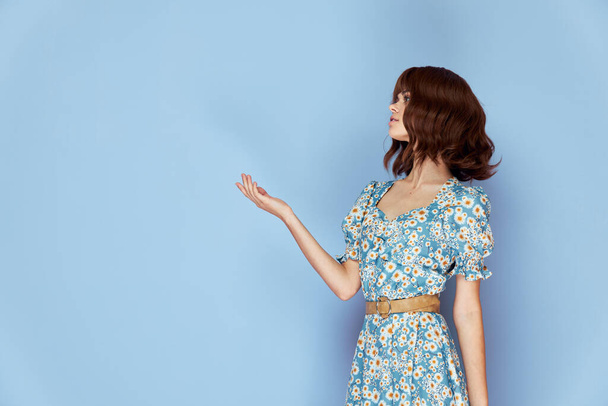 Retrato de mujer sosteniendo su mano frente a él vista lateral fondo azul  - Foto, imagen