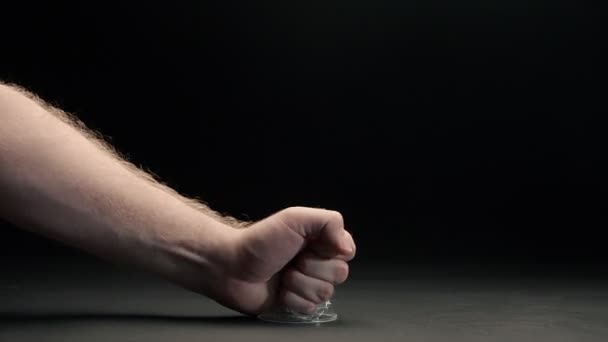 Zbliżenie męskiej pięści miażdży naciskając plastikowy kubek na czarnym tle - Materiał filmowy, wideo