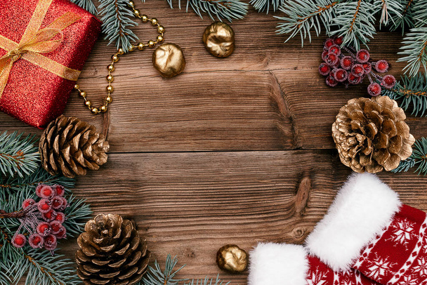 Karácsonyi keret piros ajándék doboz, kék fenyő ágak, arany kúp, bogyók és zoknik a sötét fa rusztikus hátter.Karácsonyi háttér.Másolja tér fot szöveg, felülnézet, lapos feküdt - Fotó, kép