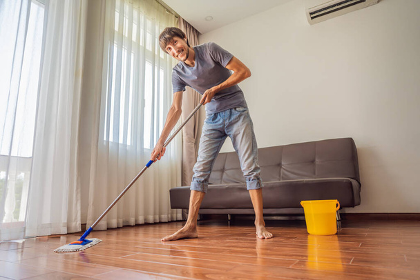 Young man with mop cleaning floor at home - Photo, Image