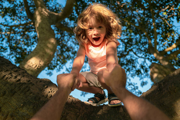 Kids climbing trees. Fathers hand. Child protection. - Zdjęcie, obraz