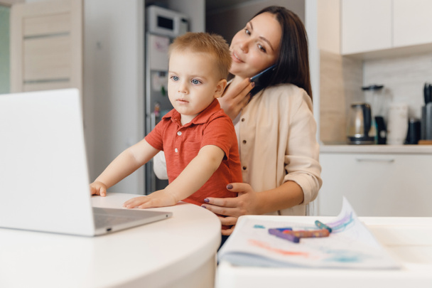 Businesswoman mother woman with kid working online computer and call phone home office - Photo, Image