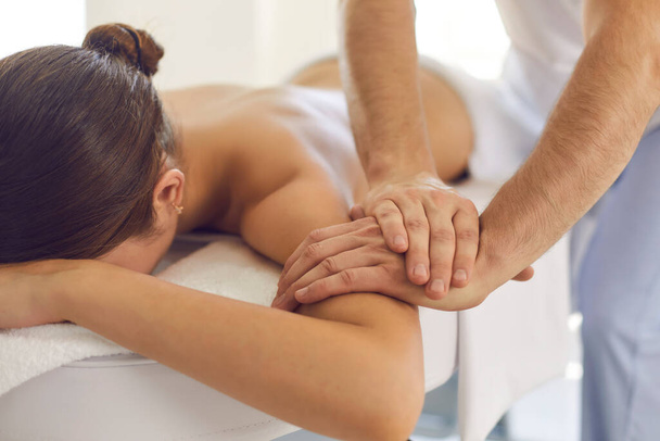 Relaxed woman getting medical body massage done by professional physiotherapist in modern clinic - Foto, Imagem