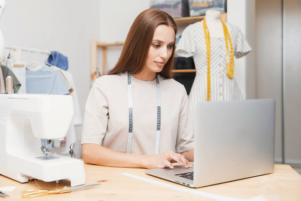 Mujer costurera diseñador de moda portátil de trabajo, tomando órdenes para coser ropa - Foto, Imagen