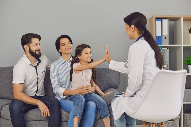 Smiling girl giving high five to woman doctor during successful consultation in clinic - Foto, Bild