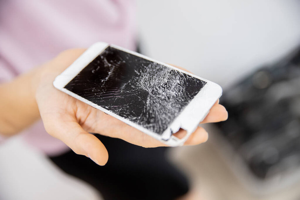 Kadının ellerinde kırık cam bir telefon ekranı, beyaz arka plan. - Fotoğraf, Görsel