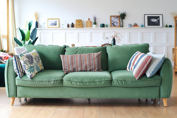 Large green upholstered sofa with pillows in the living room - Fotoğraf, Görsel
