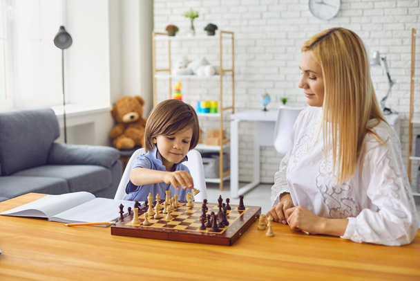 Mother and son play chess at the table at home.Happy family with parent and child enjoying board game at home - 写真・画像