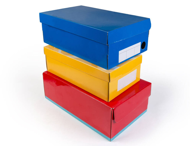 Verschiedene geschlossene Schuhkartons in verschiedenen Farben auf weißem Hintergrund gestapelt - Foto, Bild