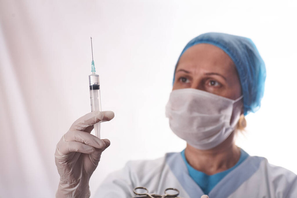 De vrouwelijke arts bereidt de spuit voor om de patiënt in de onderzoekskamer te injecteren.. - Foto, afbeelding