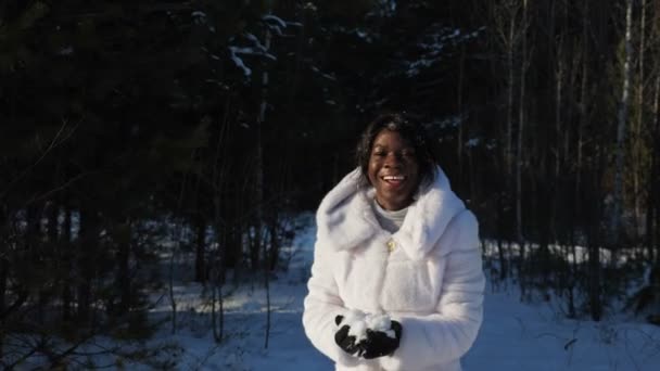 vrouw rent en kotst sneeuw vallende op donkere huid gezicht - Video
