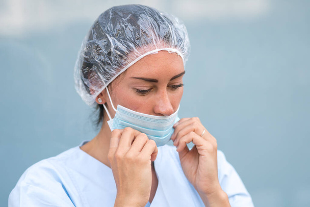 Porträt einer Ärztin, die ihre chirurgische Schutzmaske aufsetzt - Foto, Bild
