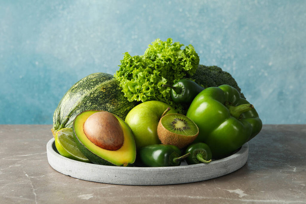 Tray with green fruits and vegetables on gray table - Photo, image