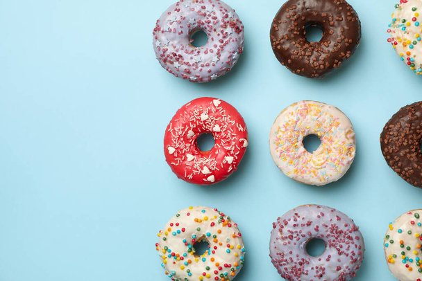 Flache Lage mit leckeren Donuts auf blauem Hintergrund - Foto, Bild