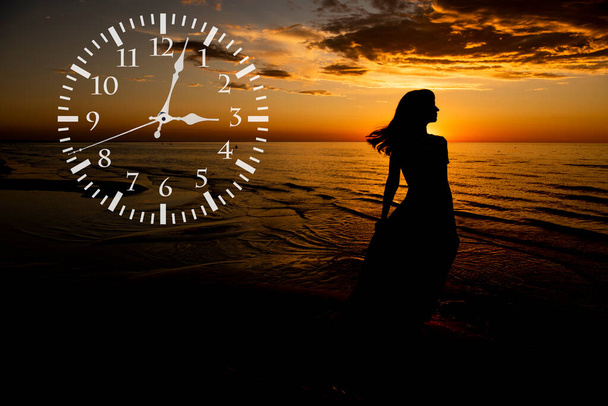 Koncept úspory času za denního světla. Mladá žena s hodinami na tmavém pozadí přírody. - Fotografie, Obrázek
