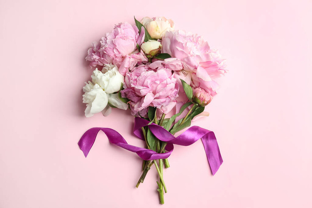 Bouquet of beautiful peonies with ribbon on pink background, flat lay - Photo, Image