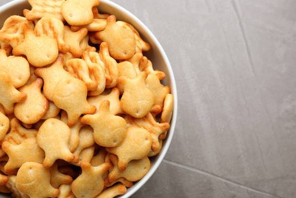 Delicious goldfish crackers in bowl on grey table, top view - Fotoğraf, Görsel