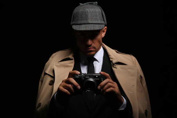 Old fashioned detective with camera on dark background - Foto, Imagen