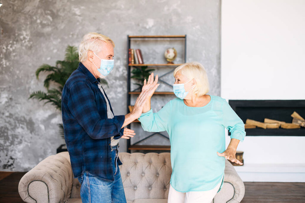 Senior couple wearing face masks dancing indoors - Foto, Bild