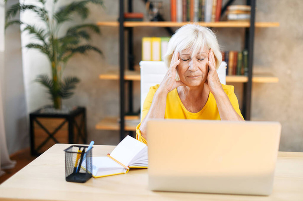 Tired senior business woman is using laptop - Fotó, kép