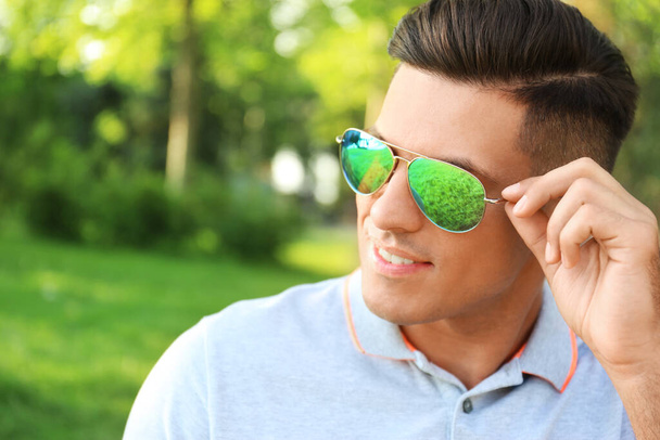 Handsome man wearing stylish sunglasses in park. Space for text - Fotografie, Obrázek