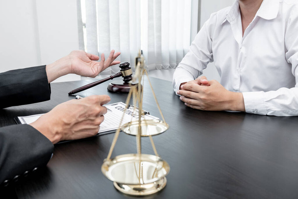 A male lawyer or a judge counseling clients about judicial justice and prosecution with scales, judges gavel, legal documents legal services concept. - Photo, Image