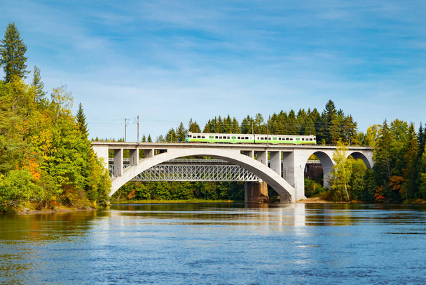 Paysage automnal du pont avec train de voyageurs en mouvement et eaux de la rivière Kymijoki en Finlande, Kouvola, Koria - Photo, image