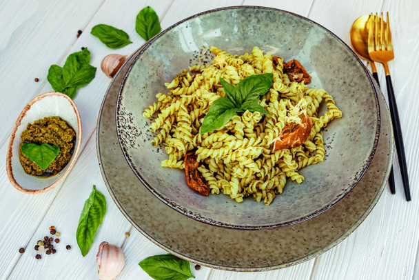  Italian pasta with pesto sauce and sun-dried tomatoes on a white wooden table. High quality photo - Foto, afbeelding