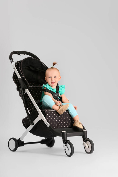 Niedliches kleines Baby im Kinderwagen auf hellem Hintergrund - Foto, Bild