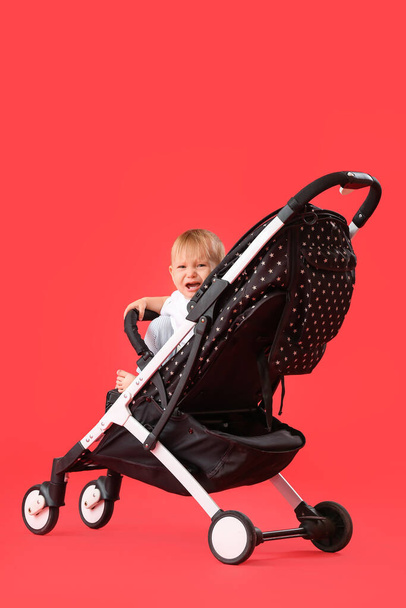 Niedliches kleines Baby im Kinderwagen auf farbigem Hintergrund - Foto, Bild