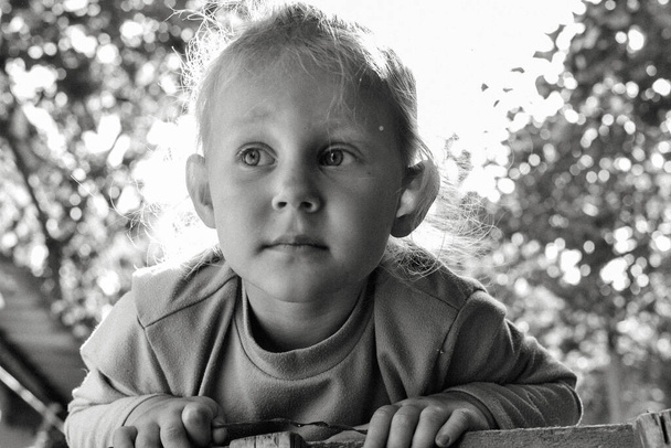 Close-up zwart-wit portret van schattige schattige glimlachende blanke kind. Portret van een gelukkig kind in de natuur. Gelukkige kindertijd concept. De baby kijkt in de camera. De oprechte emoties van het kind - Foto, afbeelding