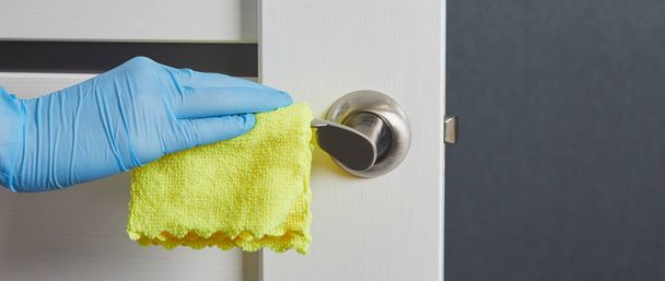 Naisen kädet desinfioida, puhdistaa ja pestä oven kahvat. Sepelvaltimotautitartunnan ehkäisy COVID-19:n aikana. Valkoinen ovi. - Valokuva, kuva