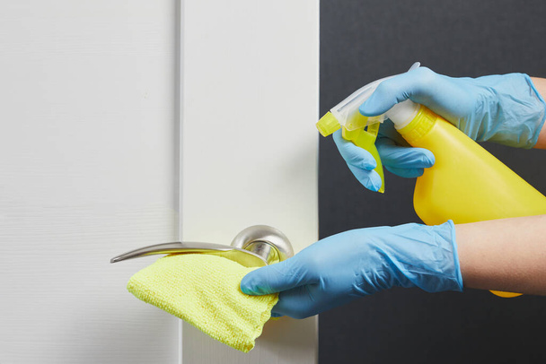 Female hands disinfect, clean and wash of door handles. Prevention of coronavirus infection during the COVID-19. White door. - Foto, Bild