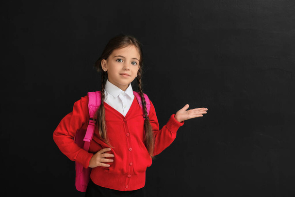 Little schoolgirl showing something on dark background - Фото, зображення