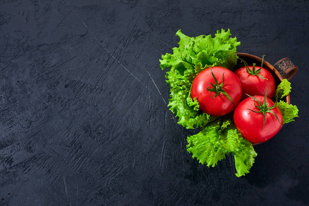 Fresh grape tomatoes with salad Leaves on black stone background. Vegan veggies diet food. Herb, tomatoes, cooking concept. - Fotoğraf, Görsel