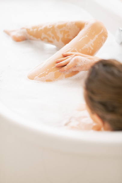 Young woman washing in bathtub - Fotó, kép