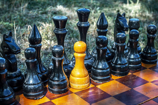 Witte schaakpion met zwarte stukken op het schaakbord. Het concept van spionage, verraad, agenten. - Foto, afbeelding